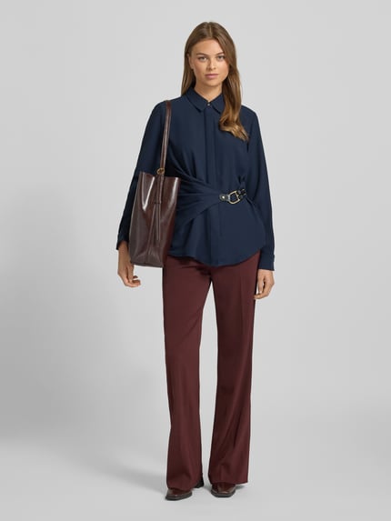 Frauenmodel trägt Bluse in Wickel-Optik Modell 'KRESHAY' von Lauren Ralph Lauren, taillierter Schnitt, Hemdblusenkragen, Schnalle, Ganzkörperansicht von vorne.