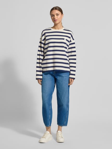 Vrouwenmodel draagt High Waist Barrel Jeans uit puur katoen model 'BAARLY' van Armedangels in denimlook met barrel fit, enkellengte, labelpatch, met studs, riemlussen, knoop- en ritssluiting, 5-pocketmodel, puur katoen; gehele lichaamsaanzicht van voren.