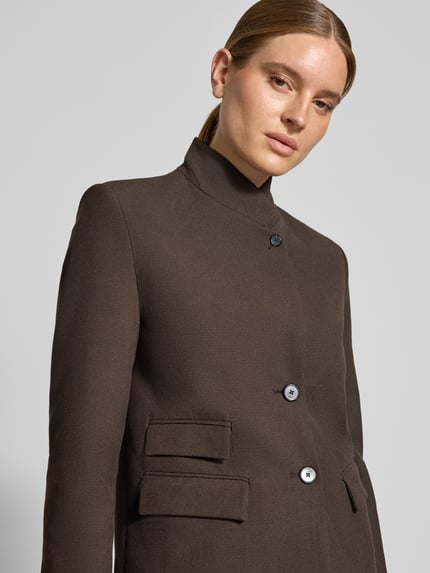 Frauenmodel trägt Regular Fit Blazer mit Stehkragen Modell 'LEO' von MANGO, Material-Mix, Knopfverschluss, braun, Nahaufnahme Oberkörper.