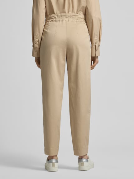 Frauenmodel trägt Straight Fit Stoffhose mit Tunnelzug von Marc Cain, beige, Baumwoll-Mix, Teilelastikbund, Ganzkörperansicht Rückansicht.
