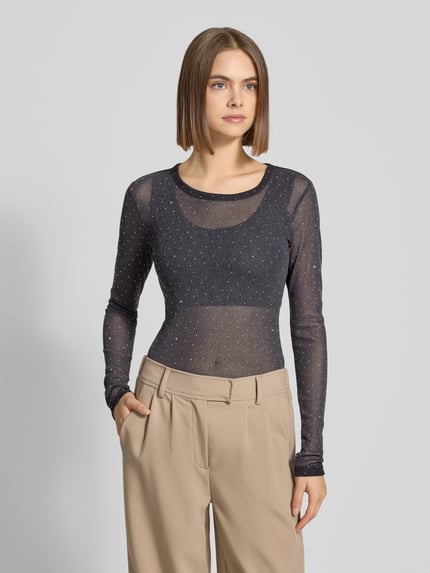 Frauenmodel trägt Slim Fit Longsleeve mit Strasssteinbesatz von Gina Tricot, schwarzer semitransparenter Stoff, Rundhalsausschnitt, Nahaufnahme Oberkörper.