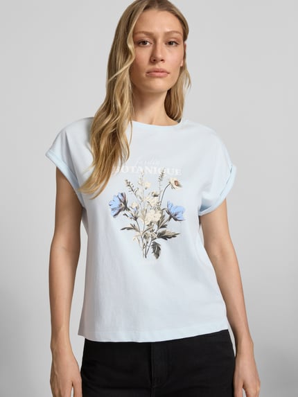 Modelka nosi damski t-shirt Relaxed Fit T-Shirt aus reiner Baumwolle von s.Oliver RED LABEL, efekt: jednolity kolor, krój relaxed fit, nadruk z przodu, nadruk z logo, ramiona obniżone, okrągły dekolt, krótki rękaw z brzegiem, materiał: bawełna; jasne kolory, motyw kwiatowy; zbliżenie na górną część ciała, widok z przodu.