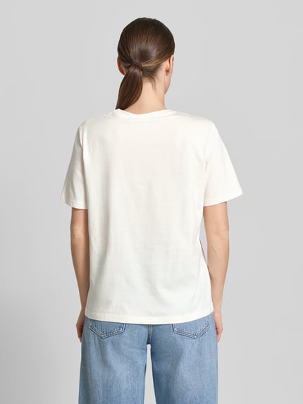 Vrouwenmodel draagt T-shirt met motiefprint model 'SYBIL' van Vila in puur katoen, recht model, ronde hals, ruglengte maat S 60 cm, volledig wit, gladde textuur, Ganzkörperansicht Rückansicht.
