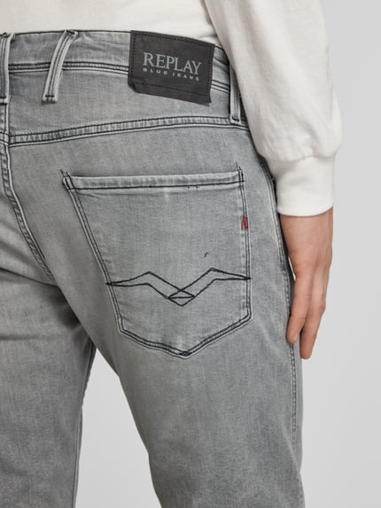 Mężczyznamodel nosi Slim Fit Jeans mit Eingrifftaschen Modell 'Anbass' von Replay, mieszanka bawełny i elastanu, krój slim fit, wpuszczane kieszenie, szerokość w rozmiarze 32/32: 44 cm, długość wewnętrzna nogawki 32/32: 81 cm, szary denim z widocznym szwem, detailaufnahme z tyłu.