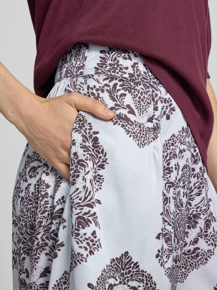 Frauenmodel trägt Wide Leg Pants mit Eingrifftaschen Modell 'Lunet' von Neo Noir, Muster in Weiß und Dunkellila, Nahaufnahme Oberkörper, elastischer Bund, französische Eingrifftaschen, Bundweite 37 cm, Innenbeinlänge 78 cm bei Größe 36.