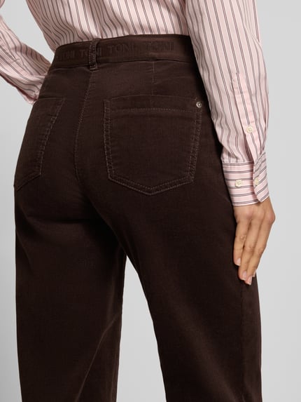 Frauenmodel trägt Regular Fit Cordhose mit seitlichen Eingrifftaschen Modell 'Jenny Wide' von TONI, brauner Cord mit Strukturmuster, Detailaufnahme Rückansicht.