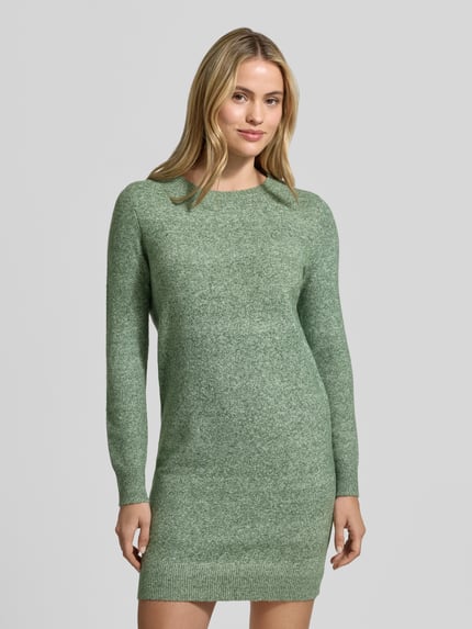 Frauenmodel trägt tailliertes Strickkleid mit Rundhalsausschnitt Modell 'DOFFY' von VERO MODA in melierter Strickoptik, Regular Fit Mini, Ganzkörperansicht von vorne.