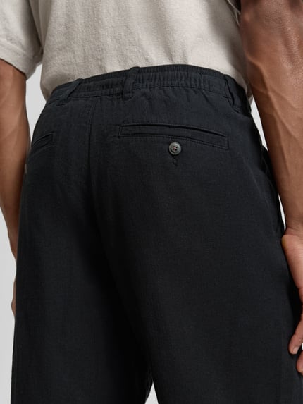 Männermodel trägt Loose Fit Leinenhose mit Tunnelzug Modell 'BRODY' von Selected Homme, Optik: Unifarben, Flammgarn, Detailaufnahme Rückansicht. Bio-Baumwoll-Leinen-Mix.
