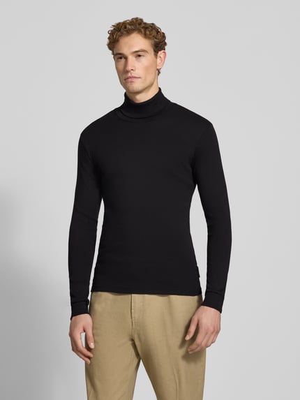 Männermodel trägt schwarzes Regular Fit Langarmshirt aus reiner Baumwolle von Marc O'Polo, helle Hose, Ganzkörperansicht von vorne. Herren Langarmshirt von Marc O'Polo.