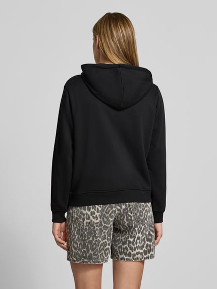 Frauenmodel trägt Relaxed Fit Sweatjacke aus Baumwoll-Mix Modell 'CHILLI' von PIECES in Schwarz, glatte Oberfläche, Ganzkörperansicht Rückansicht.