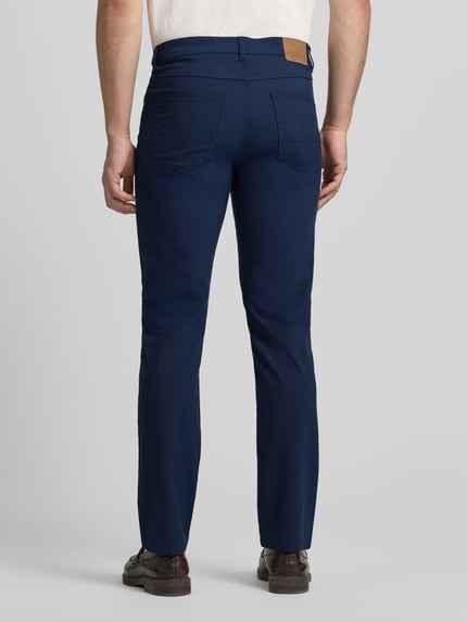 Männermodel trägt Chino mit 5-Pocket-Design von Christian Berg Men in Dunkelblau, gerader Schnitt, Material-Mix, Ganzkörperansicht Rückansicht.