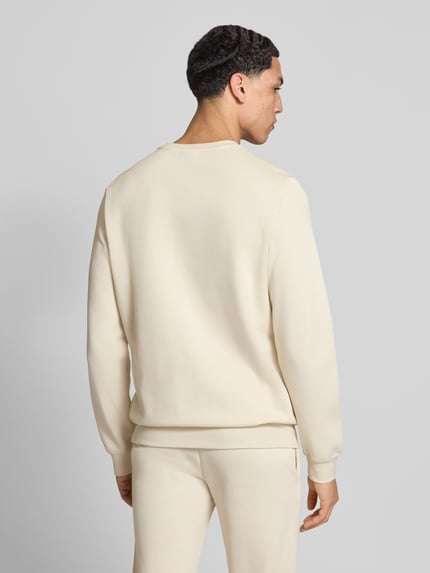 Mężczyzna nosi Regular Fit Sweatshirt mit Logo-Stitching od PUMA PERFORMANCE z mieszanki bawełny, okrągły dekolt, elastyczne wykończenia, jasny kolor, długość tyłu 69 cm, długość rękawów 69 cm, zdjęcie całej sylwetki z tyłu.