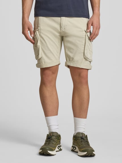 Männermodel trägt Shorts mit Cargotaschen Modell 'CREW SHORT' van Alpha Industries in beige, regular fit van katoen-elastaan, Ganzkörperansicht von vorne, heren shorts context: taillewijdte maat 32: 44 cm, binnenbeenlengte maat 32: 22 cm.