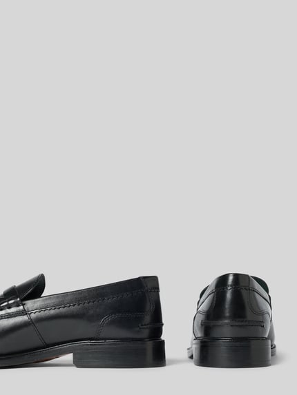 Produktfoto, Slipper aus beschichtetem Leder Modell 'CraftJames' von Clarks in Schwarz mit glatter Sohle und Zierriemen, abgerundete Form, Absatzhöhe 3 cm, Schafthöhe 7 cm, Schaftweite 12 cm, neutrale Hintergrundfarbe
