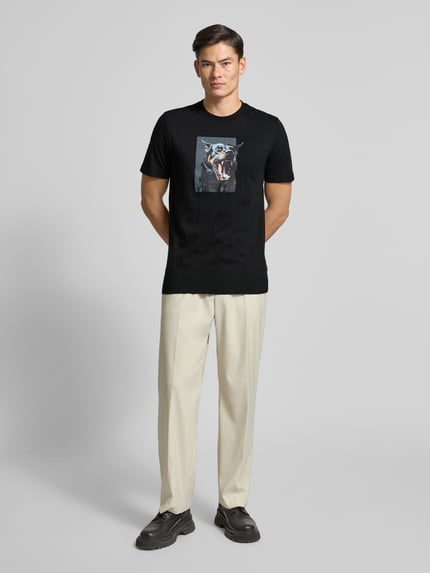 Männermodel trägt Slim Fit T-Shirt aus reiner Baumwolle Modell 'TE_DOBERMANN' von BOSS Orange, Optik: Unifarben, Animal-Print, Rundhals, Kurzarm, Materialverarbeitung: Jersey, Farbe Schwarz, glatte Textur, Ganzkörperansicht von vorne.
