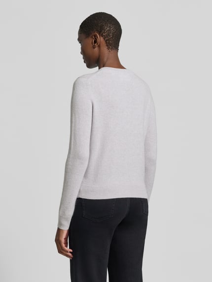 Frauenmodel trägt Strickjacke aus reinem Kaschmir mit durchgängiger Knopfleiste von Christian Berg Woman, hellgraue Farbe, gerippte Abschlüsse, Rückansicht, Regular Fit, Damen Strickjacke, langärmliges Design, strukturierte Textur, Kontext: Rückenlänge 55 cm, Ärmellänge 63 cm. Ganzkörperansicht Rückansicht
