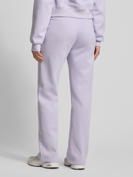 Frauenmodel trägt Sweatpants mit elastischem Bund Modell 'Iconic' von Gina Tricot aus Baumwoll-Mix in Relaxed-Fit, Ganzkörperansicht Rückansicht.