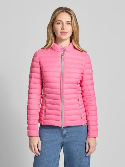 Frauenmodel trägt Steppjacke mit Zweiwege-Reißverschluss Modell 'JUDY' von Frieda & Freddies in Pink, Slim Fit, Stehkragen, Reißverschlusstaschen, Rückenlänge 57 cm, Schulterbreite 40 cm, Brustweite 48 cm, Ärmellänge 64 cm, Ganzkörperansicht von vorne.