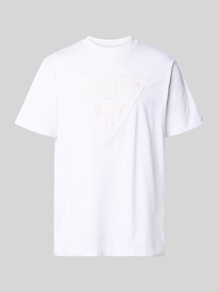 Produktfoto, T-Shirt mit Logo und Rundhalsausschnitt von Guess in Weiß, Baumwolle, Regular Fit, dezentes Logo, glatte Struktur, Rückenlänge 70 cm.
