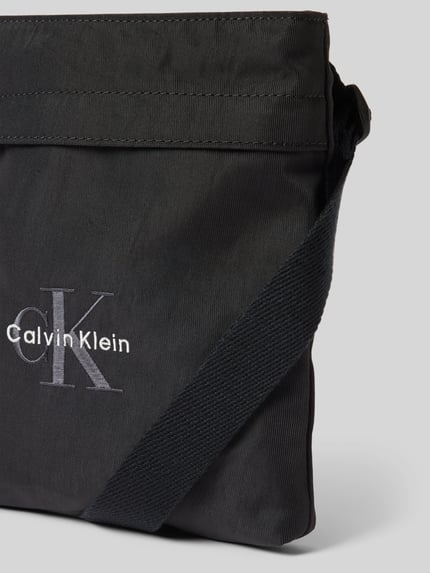 Produktfoto, schwarze Crossbody Bag mit Label-Stitching von CK Calvin Klein, rechteckig, grobe Textilstruktur, Reißverschluss, Detailaufnahme