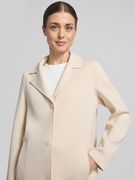 Frauenmodel trägt Regular Fit Kurzmantel mit Kapuze von s.Oliver RED LABEL in Beige, unifarbenes Scuba-Material, Nahaufnahme Oberkörper.
