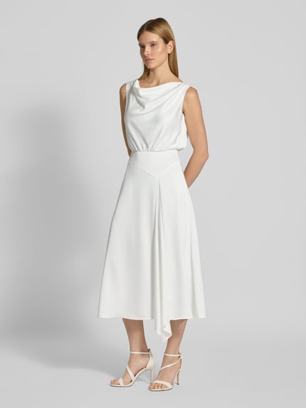 Frauenmodel trägt Brautkleid mit Wasserfall-Ausschnitt von SWING, taillierter Schnitt, fließender Stoff, weiß, Midikleid, Ganzkörperansicht von vorne.