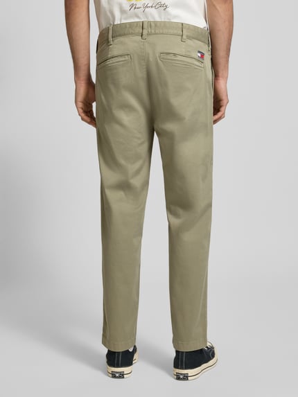 Männermodel trägt Tapered Chino aus Baumwoll-Mix Modell 'SONNY' von Tommy Jeans, Optik: Unifarben, Twill, Ganzkörperansicht Rückansicht.