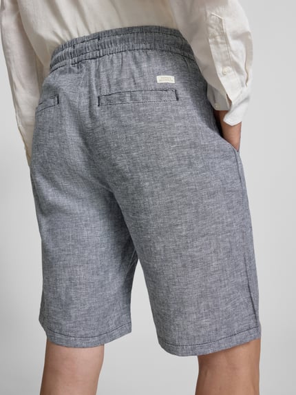 Männermodel trägt Shorts aus Leinen-Mix mit Eingrifftaschen Modell 'MARCO' von Blend, meliertes Grau, elastischer Bund, Ganzkörperansicht Rückansicht.