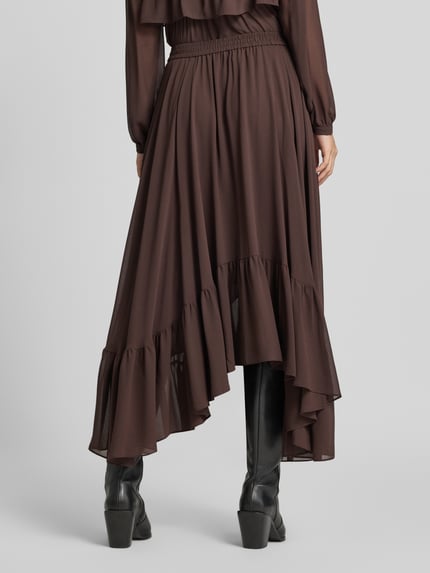 Frauenmodel trägt Midi-Rock aus Chiffon in asymmetrischem Look von MICHAEL Michael Kors in Braun, fließende A-Linie, Ganzkörperansicht Rückansicht