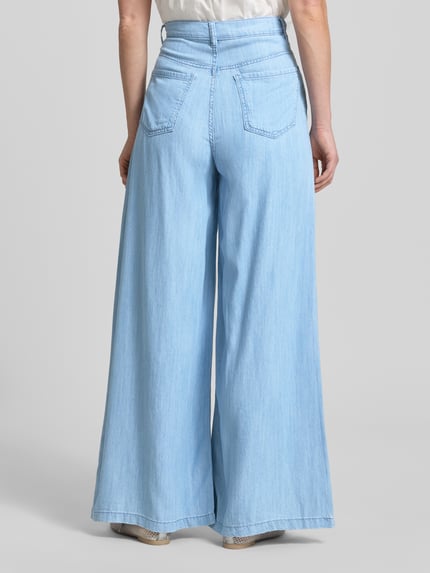 Frauenmodel trägt helle Wide-Fit Jeans aus Lyocell-Mix Modell 'Eva' von Mango mit Eingriff- und Gesäßtaschen, Ganzkörperansicht Rückansicht.