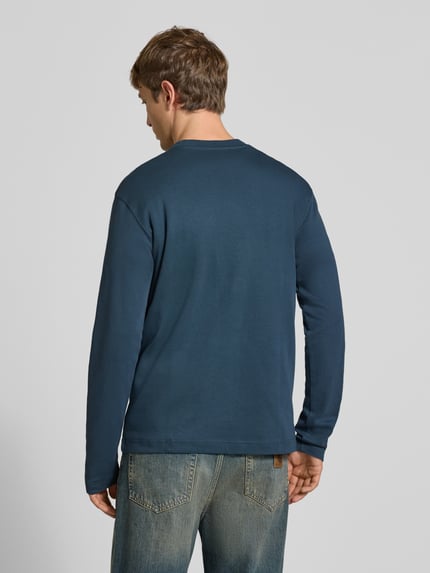 Männermodel trägt Langarmshirt mit kleinem Logo-Schriftzug von G-Star RAW in Dunkelblau, Strukturmuster, Regular Fit, Ganzkörperansicht Rückansicht.