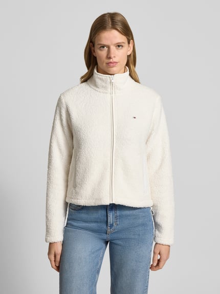 Kobiece modelka nosi Regular Fit Teddy-Jacke mit verdecktem Reißverschluss od Tommy Jeans, imitacja futerka, jednolity kolor, stójka, wyhaftowane logo, długi rękaw, kieszenie na zamek błyskawiczny, wykończenie materiału: futerko, Ganzkörperansicht von vorne.