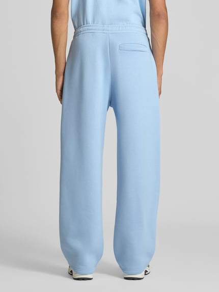 Männermodel trägt Straight Fit Sweatpants Baumwoll-Mix von REVIEW in Hellblau, Gesäßtasche, elastischer Bund, Ganzkörperansicht Rückansicht.