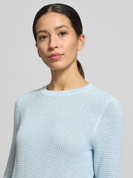 Frauenmodel trägt Strickpullover mit gerippten Abschlüssen Modell 'dalo' von Vila in Hellblau, reine Baumwolle, Slim Fit, Nahaufnahme Oberkörper.