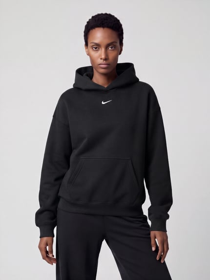 Frauenmodel trägt Oversized Fit Hoodie aus reiner Baumwolle von Nike, unifarben schwarz, Strukturmuster, Logo-Detail, Ganzkörperansicht von vorne.