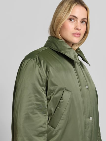 Frauenmodel trägt Daunenjacke mit Webpelzkragen Modell 'DAIMI' von BAUM & PFERDGARTEN, unifarben, glänzend, Struktur, Nahaufnahme Oberkörper.