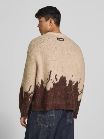 Männermodel trägt Strickpullover mit gerippten Abschlüssen von ANOTHER COTTON LAB, beige-braune Farbverläufe, elastischer Material-Mix, gerade Passform, Rückenansicht, Ganzkörperansicht Rückansicht.