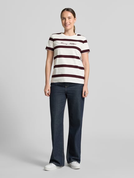 Damesmodel draagt Regular Fit T-shirt uit puur katoen van Tommy Hilfiger met brede witte en bordeauxrode strepen, Ganzkörperansicht von vorne.