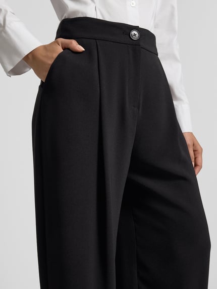 Kobieta nosi Relaxed Fit Hose mit Bundfalten od ARMANI EXCHANGE, czarne, szerokie nogawki, kieszenie, guzik i zamek, zbliżenie talii