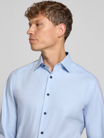 Männermodel trägt Regular Fit Businesshemd mit Kontrastknöpfen von OLYMP, hellblauer Baumwollmix, unifarben, Nahaufnahme Oberkörper.