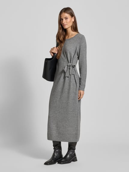 Frauenmodel trägt Relaxed Fit Kleid aus Woll-Mix in Strick-Optik Modell 'Protect' von Comma, grauer Woll-Mix mit Modal-Anteil, Zierschleife, Rundhalsausschnitt, langärmelig, Ganzkörperansicht von vorne.