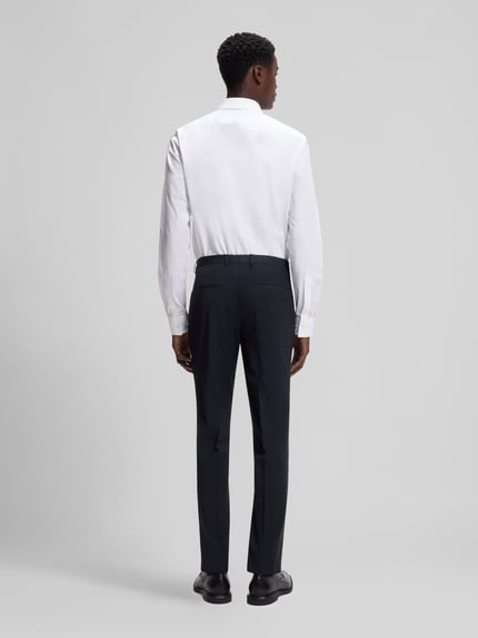 Męski model nosi Slim Fit Anzughose aus Woll-Mix Modell 'HESTEN' von HUGO, gładka czerń, lekko teksturowany materiał, krój slim fit, paski zaprasowane, szlufki na pasek, kieszenie boczne i tylne, szerokość w rozmiarze 50: 45 cm, długość nogawki wewnętrznej: 79,5 cm, widok całej sylwetki z tyłu.