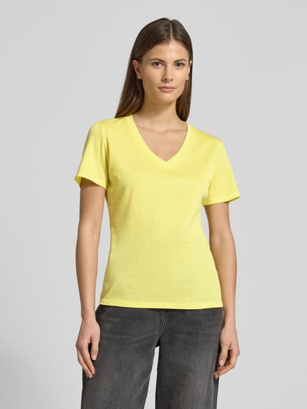Frauenmodel trägt Regular Fit T-Shirt aus Viskose-Mix von LIU JO SPORT in Gelb mit Glitzer-Optik und Logo-Detail, Nahaufnahme Oberkörper.