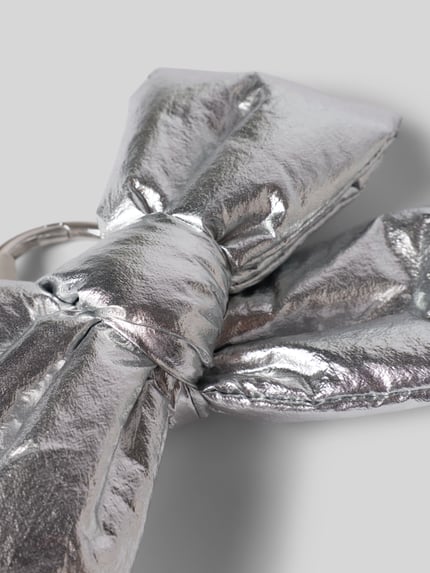 Productfoto, zilverkleurige, glanzende strikvormige textuur, Charm in Schleifen-Optik Modell 'Silver Bow' van WOUF, label-patch