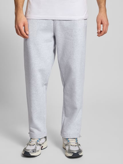Männermodel trägt Regular Fit Sweatpants mit elastischem Bund Modell 'Source' von BLKVIS z bawełny, krój regular fit, kieszeń z tyłu, długość wewnętrzna nogawki 71 cm, rozmiar M, jasnoszary kolor, gładka faktura, Ganzkörperansicht von vorne.