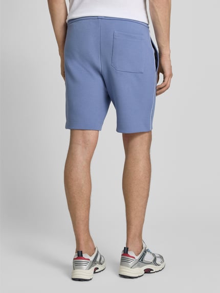 Mężczyzna model nosi Regular Fit Shorts aus Baumwoll-Mix Modell 'T_JOIN Headlo' von BOSS Green, efekt: jednolity kolor, krój regular fit, wyhaftowane logo, kanty, paski w kontrastowym kolorze, tunel, elastyczny ściągacz, kieszeń z tyłu, materiał: mieszanka bawełny, wykończenie stretch; Ganzkörperansicht Rückansicht.