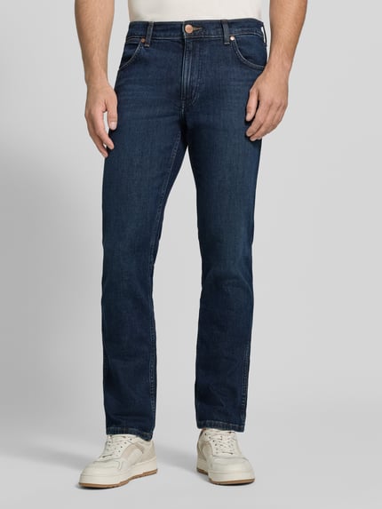 Männermodel trägt Straight Fit Jeans aus Baumwoll-Mix Modell 'Greensboro' von Wrangler in Dunkelblau, glatte Textur, Ganzkörperansicht von vorne. Herren Straight Fit Jeans von Wrangler.