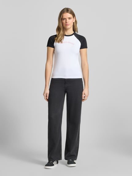 Vrouwenmodel draagt Slim Fit T-shirt met ronde hals en logo van Guess Jeans uit mix van katoen en elastaan, ruglengte maat S 53 cm, ganzebodyvooraanzicht.