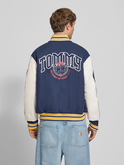 Mężczyzna nosi Regular Fit bomberka z mieszanki wełny model 'LETTERMAN' od Tommy Jeans, niebiesko-biała, duży nadruk, kontekst: bomberka/bluzon męska, Ganzkörperansicht Rückansicht