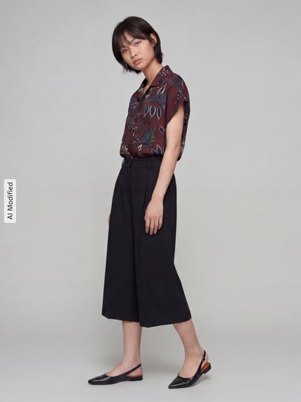 Frauenmodel trägt schwarze Weite Hose aus Viskose-Mix Modell 'MELLI S' von Brax, kombiniert mit dunkler Bluse, Ganzkörperansicht von vorne, Damen Weite Hose von Brax.